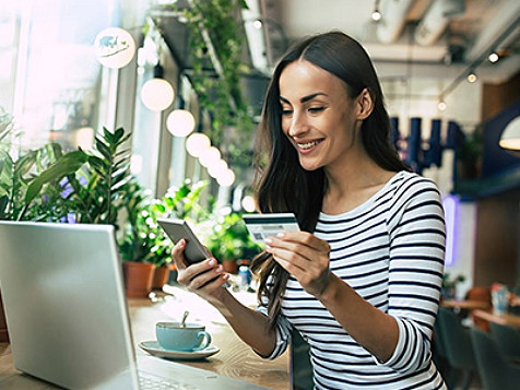A woman holding a credit card is looking into her to make a transaction