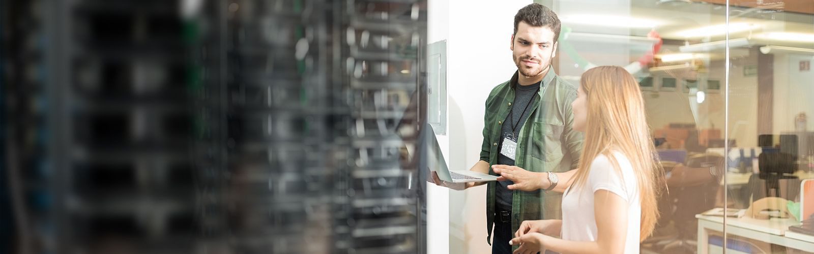 Two business people standing in server room with laptop and discussing