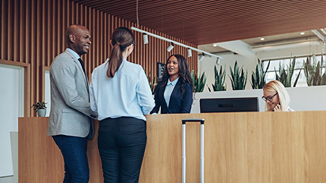 African American concierge checking in two smiling hotel guests