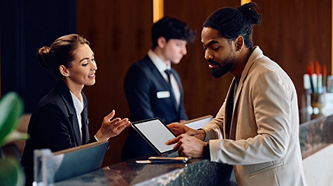 African American man checking in at reception desk in hotel.